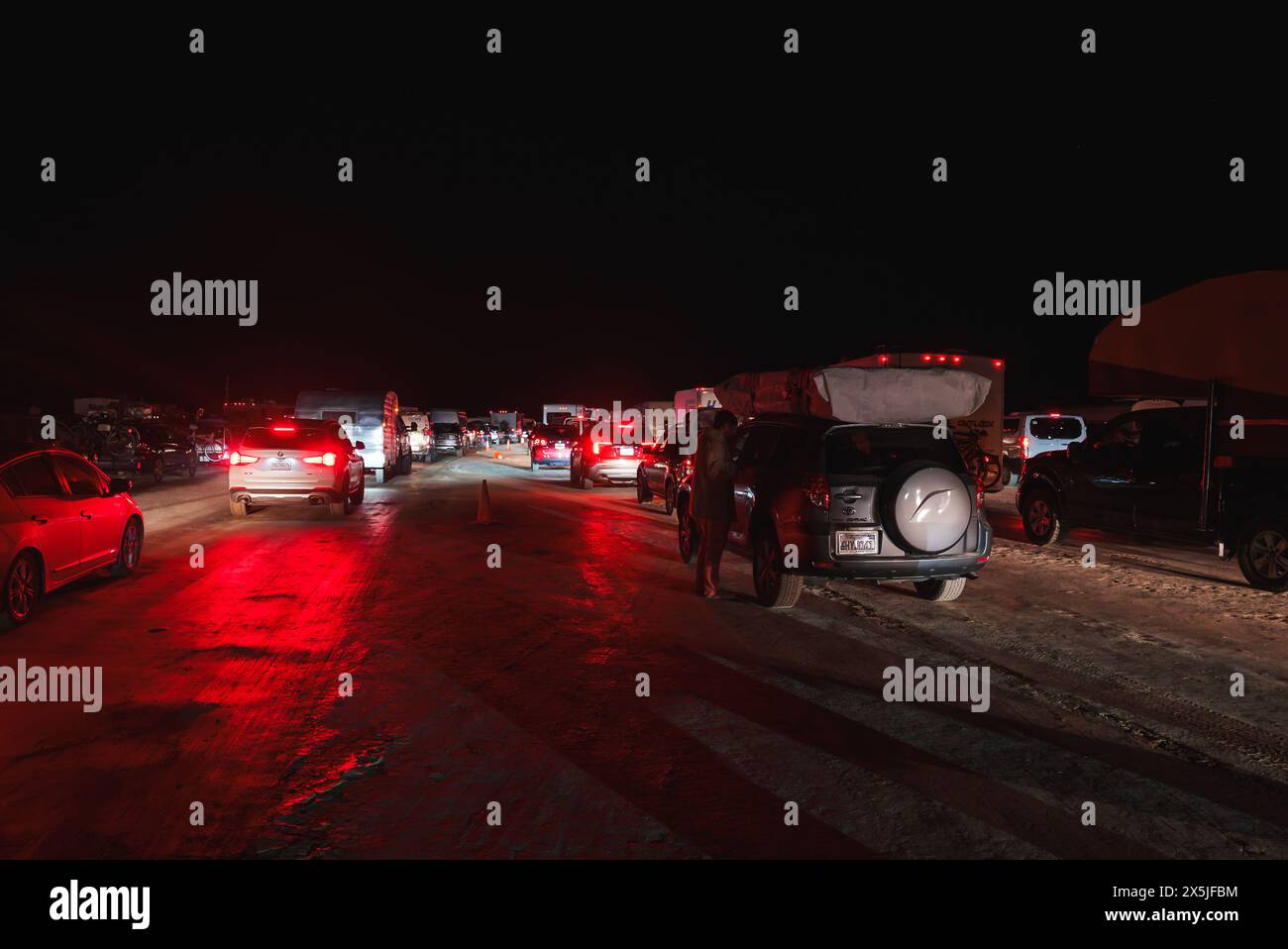 Marmellata notturna nel traffico nel deserto con luci di coda rosse che si illuminano Foto Stock