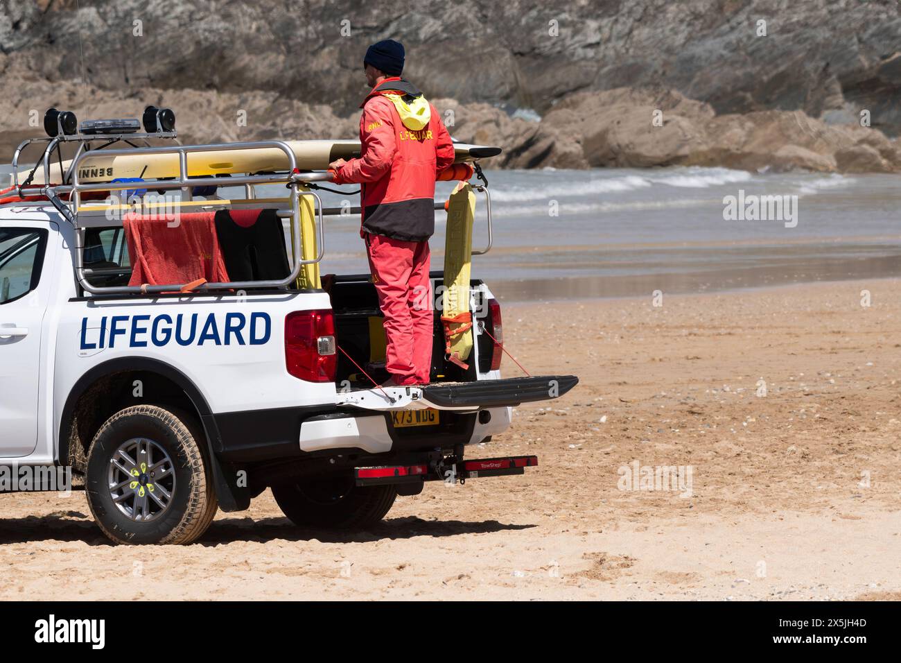 Un bagnino RNLI in servizio sul suo veicolo di emergenza parcheggiato a Fistral Beach a Newquay in Cornovaglia nel Regno Unito. Foto Stock