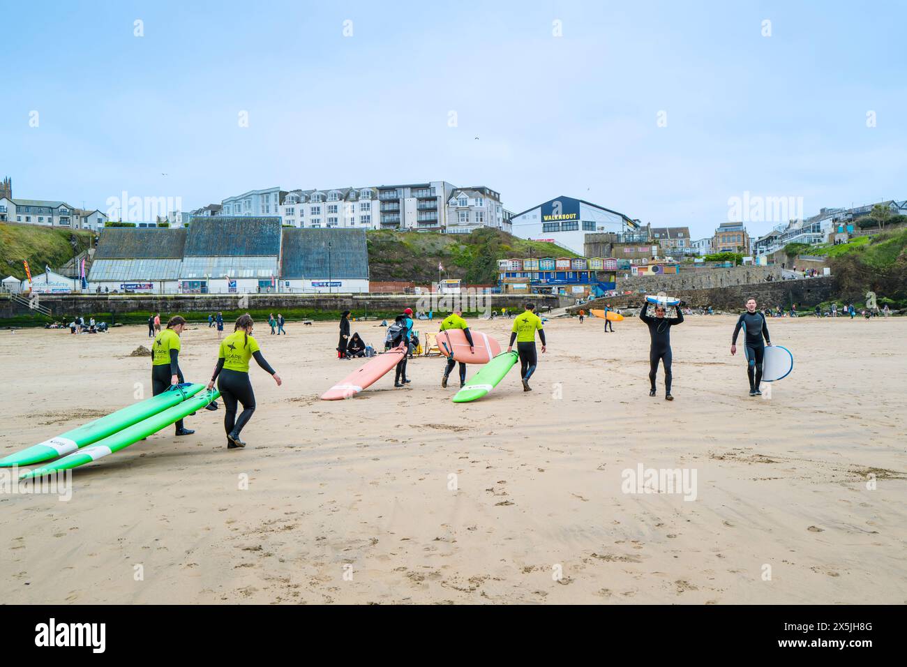 Un istruttore di surf della Escape Surf School che cammina con un gruppo di surfisti principianti sulla spiaggia di Towan a Newquay, in Cornovaglia, nel Regno Unito. Foto Stock