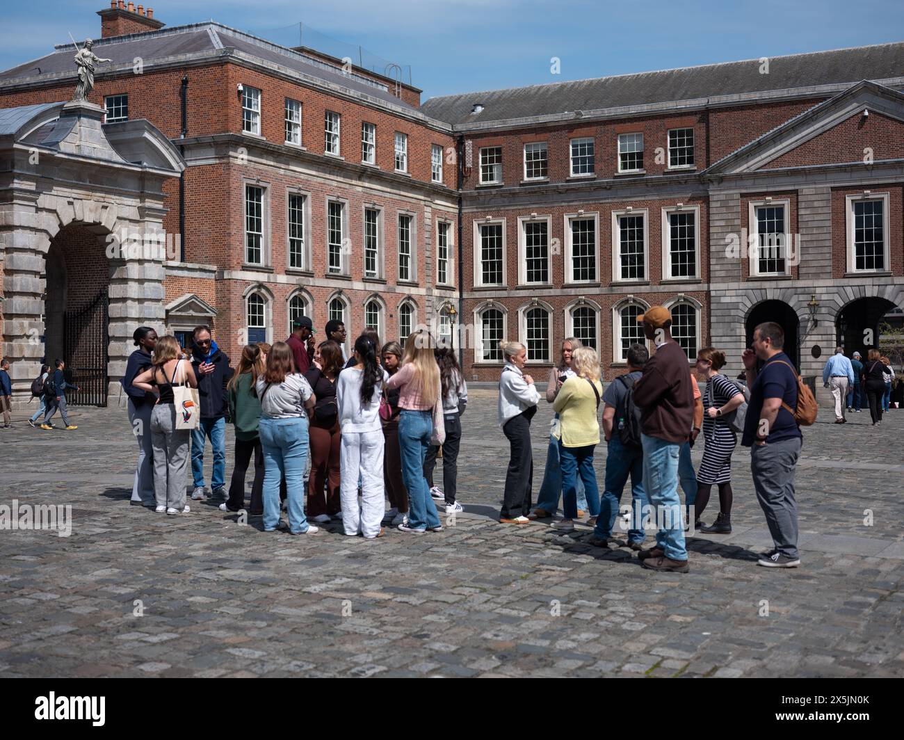 Una guida turistica che mostra le persone intorno al cortile del castello di Dublino nella città di Dublino, Irlanda. Foto Stock