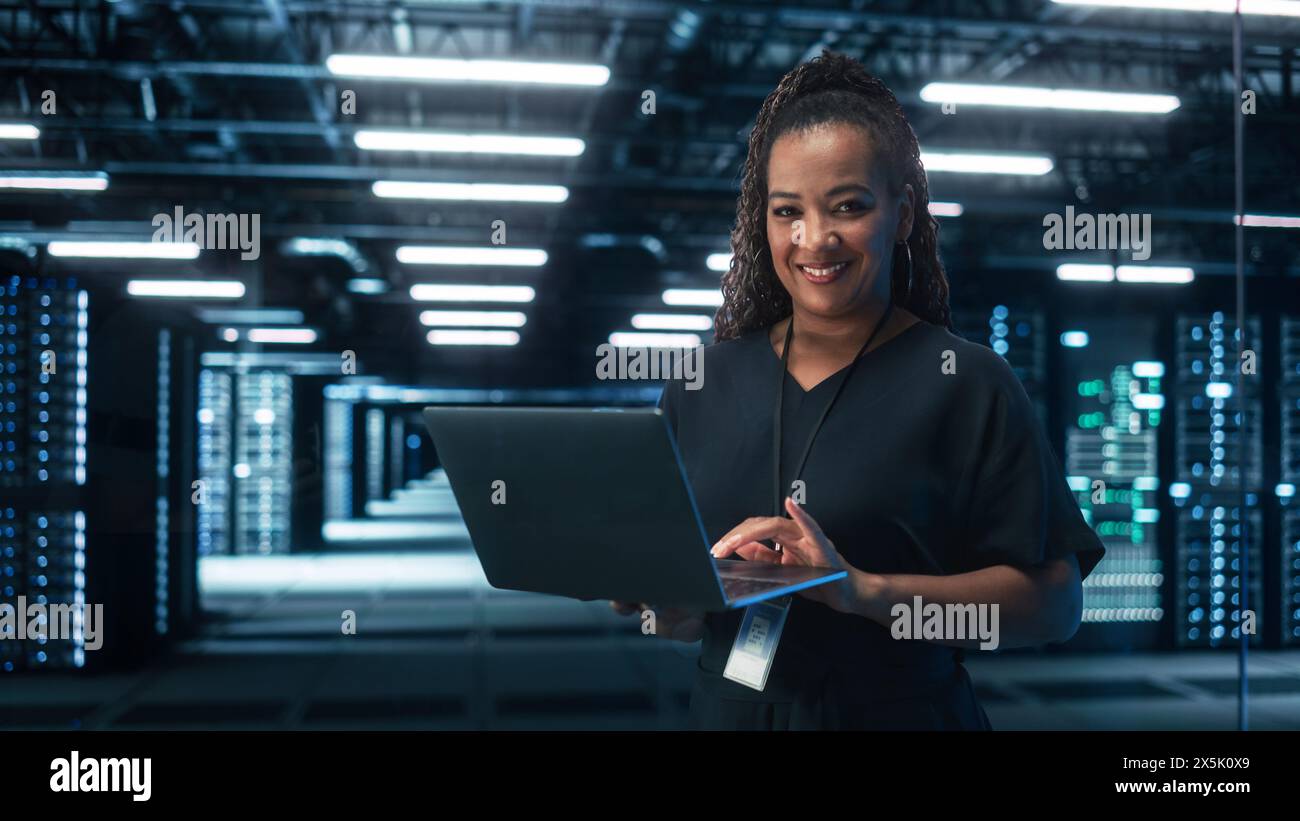 Black Female Chief Technology Office Using laptop computer, in piedi nel data center di grandi uffici. Amministratore di sistema che lavora con SAAS, Cloud Web Services. Concetto di imprenditore digitale e-Business Foto Stock