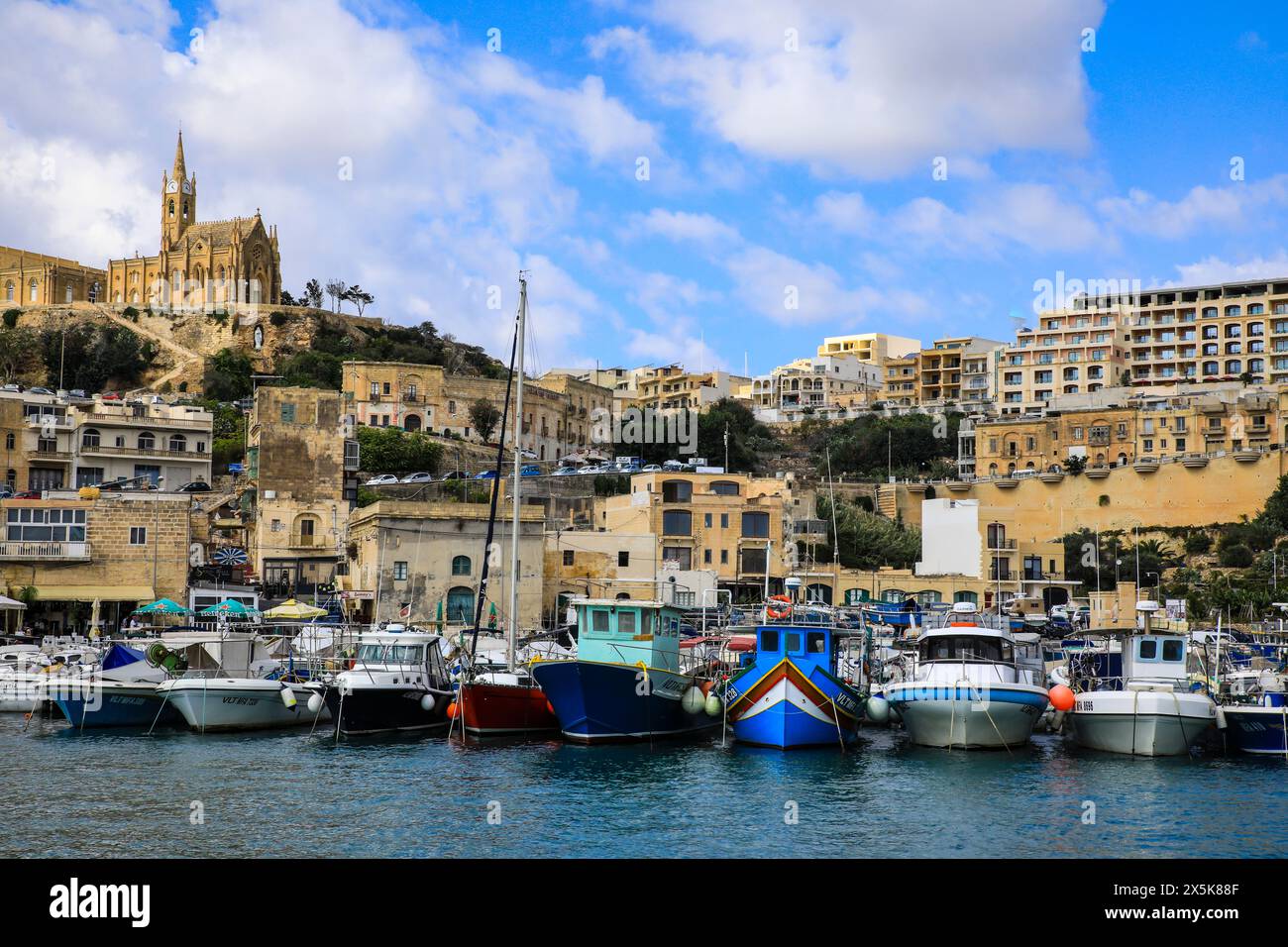 Gozo, Malta. La cattedrale della Signora di Lourdes sovrasta la città portuale e il porticciolo delle barche di Gozo Foto Stock