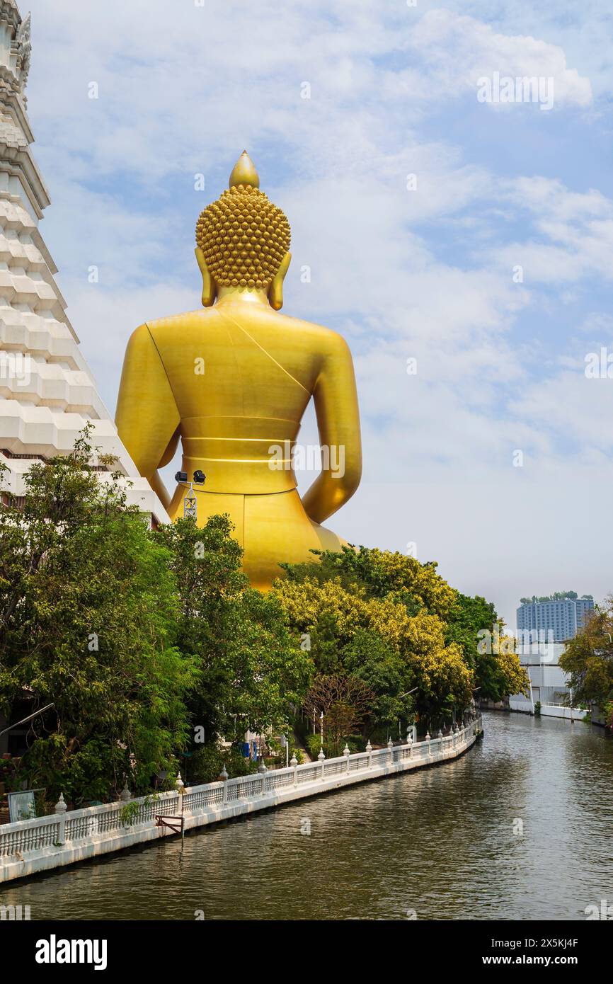 Sul retro della grande, alta e dorata statua del Buddha presso il Tempio di Wat Paknam (Pak Nam) Phasi Charoen presso un canale (khlong) a Bangkok, Thailandia, di giorno. Foto Stock