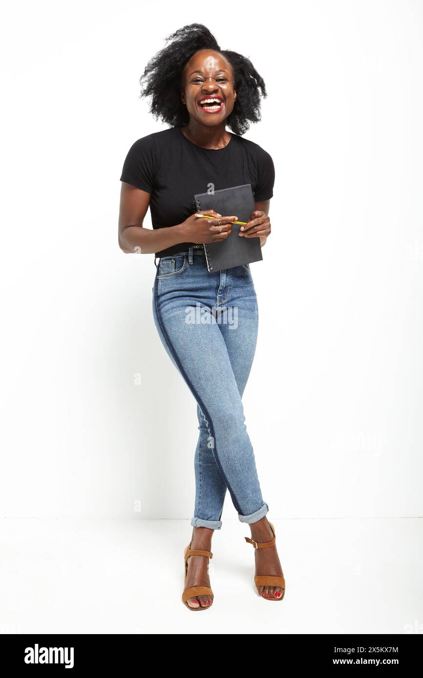 Ritratto in studio di una donna che ride in t-shirt nera e jeans Foto Stock