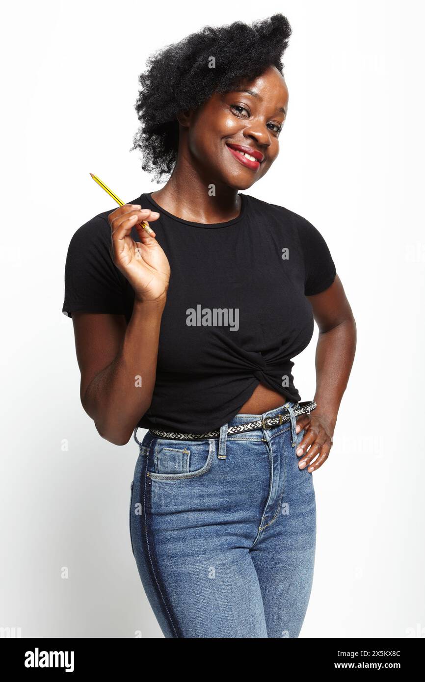 Ritratto in studio di una donna sorridente in t-shirt e jeans neri Foto Stock