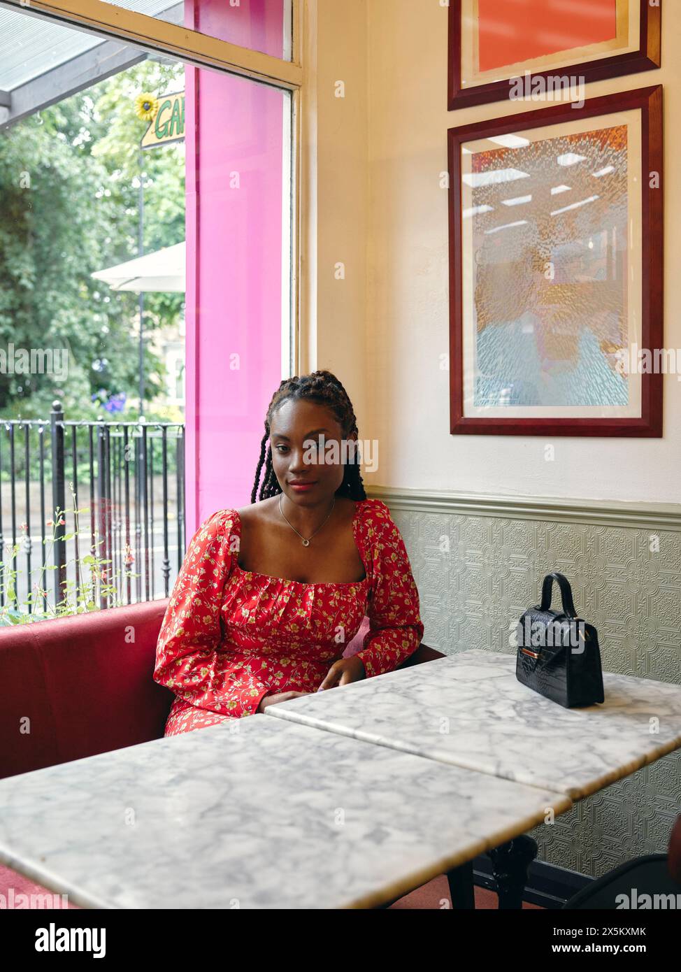 Ritratto di donna in abito rosso seduta al tavolo del bar Foto Stock