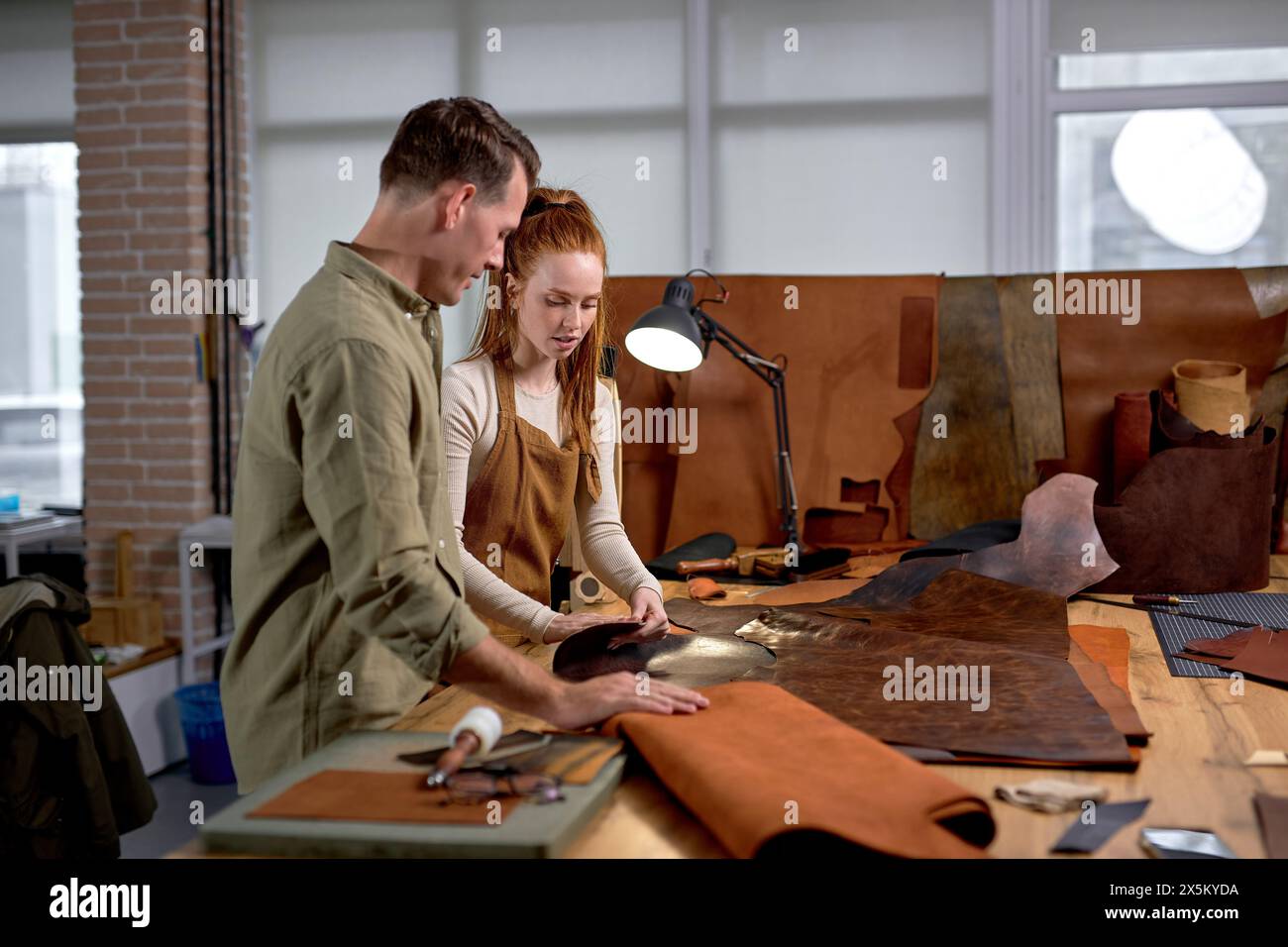 donna e uomo che controllano la superficie del materiale naturale in officina vista laterale da vicino, spazio copia Foto Stock