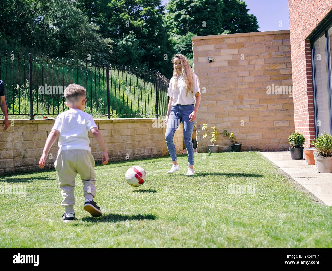 Madre con figlio che gioca a calcio nel cortile posteriore Foto Stock