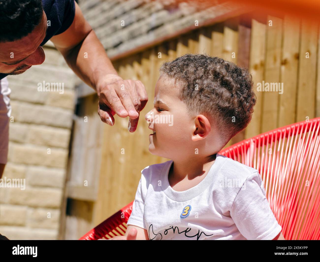 Padre che applica la crema solare sui figli affrontano all'aperto Foto Stock