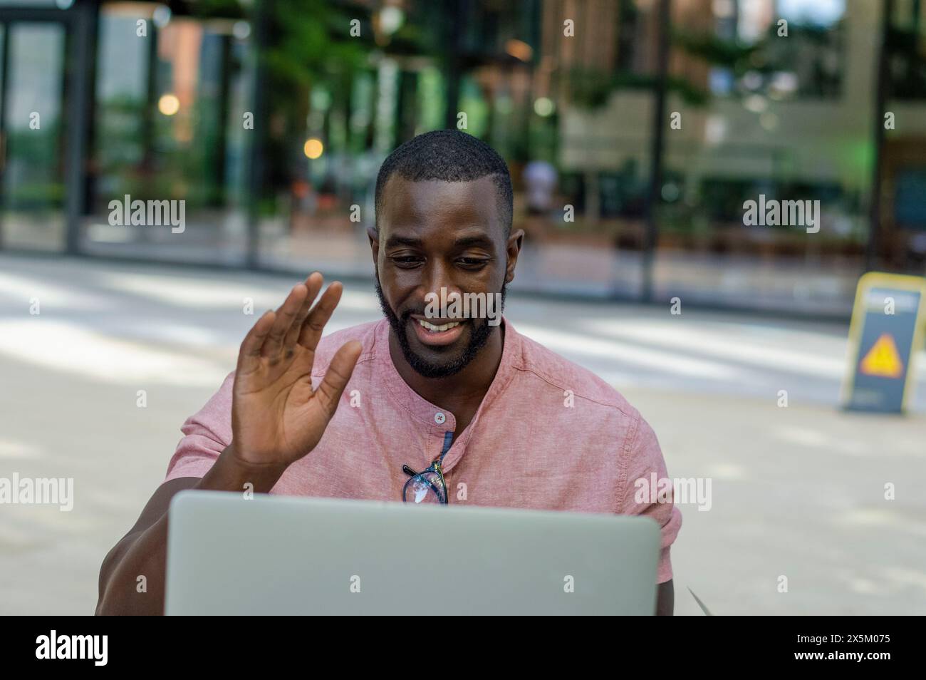 Uomo con notebook che si muove durante una conversazione online per strada Foto Stock