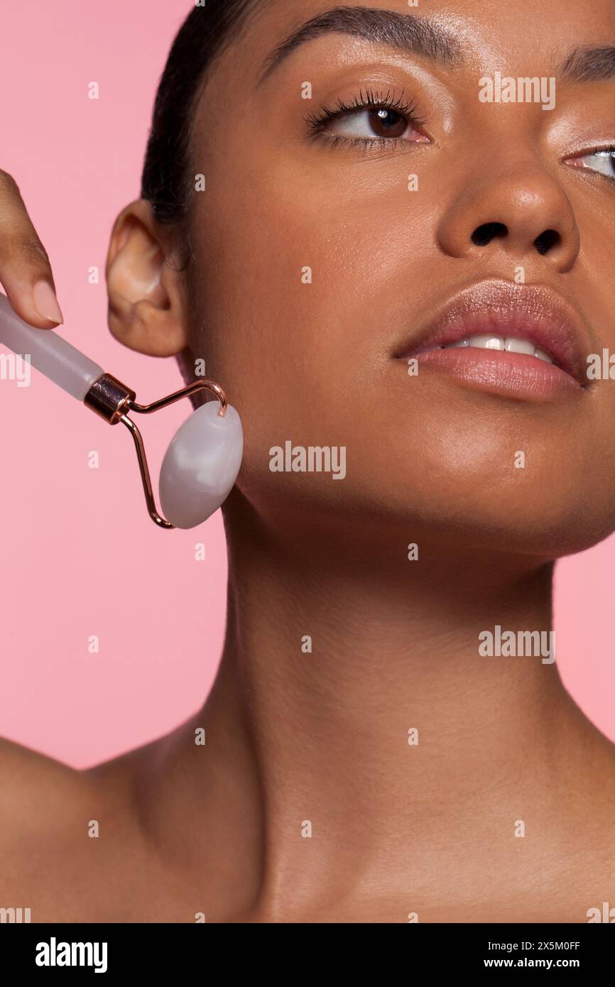 Giovane donna che usa un rullo di quarzo rosa Foto Stock