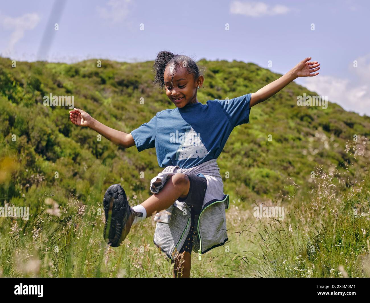 Ragazza felice con le braccia allungate che ballano sulle colline Foto Stock