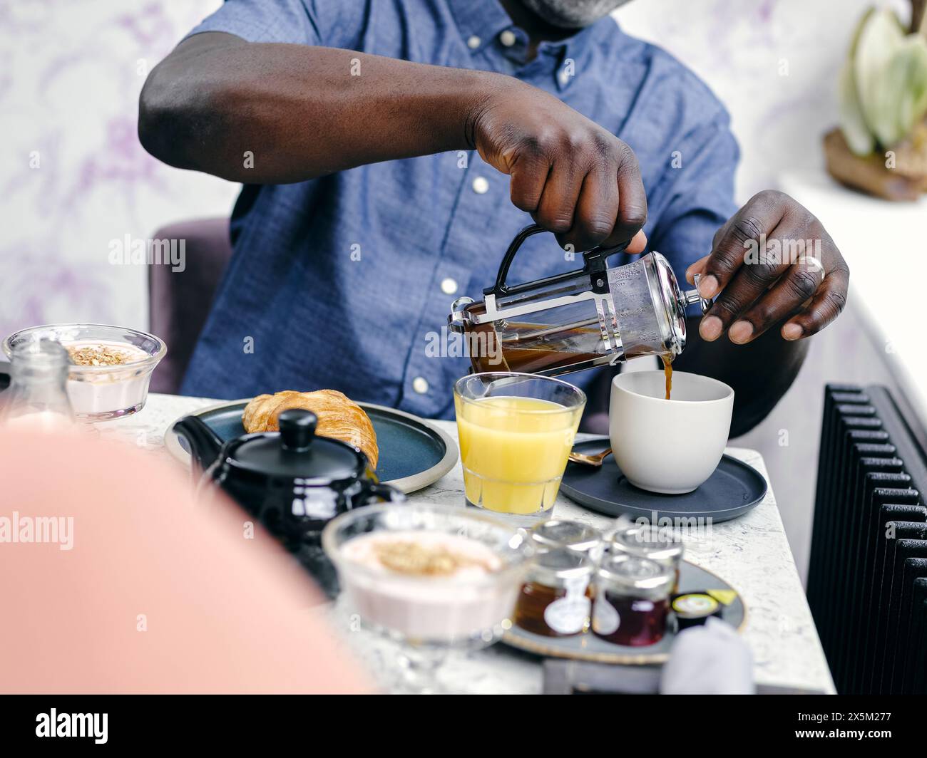 Regno Unito, uomo che versa caffè al tavolo della colazione Foto Stock