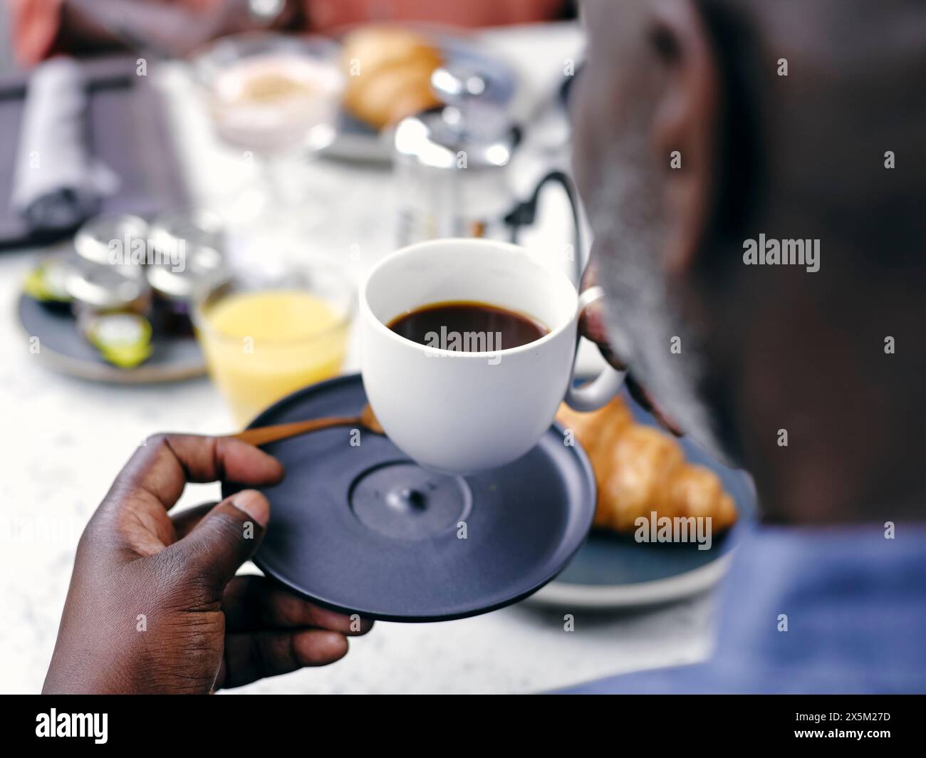 Regno Unito, primo piano di un uomo che beve caffè al tavolo della colazione Foto Stock