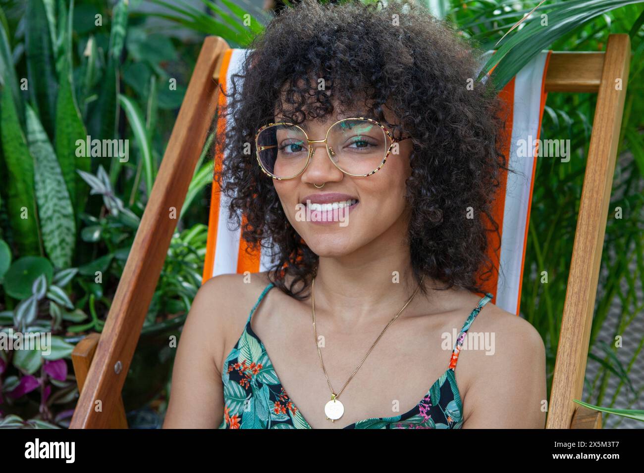 Ritratto di donna sorridente circondata da piante d'appartamento Foto Stock