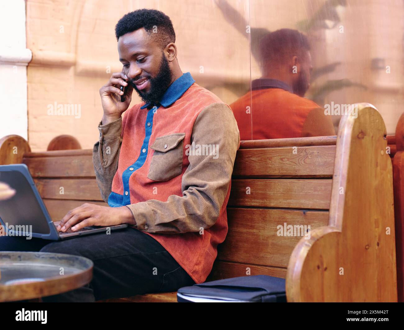 Regno Unito, Londra, uomo d'affari sorridente che usa smartphone e laptop Foto Stock