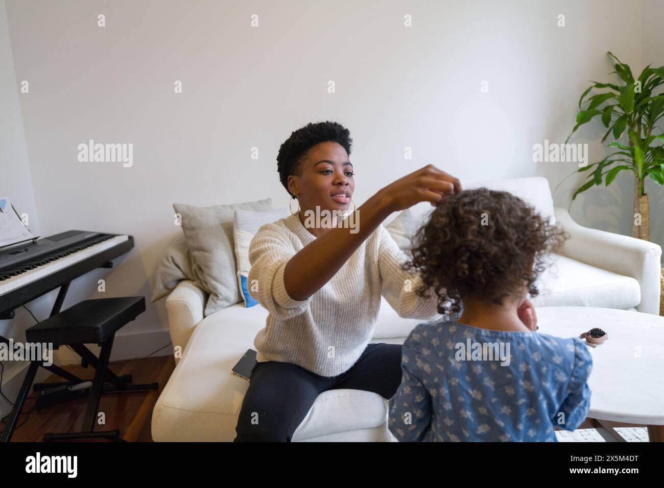 Madre che fa le figlie capelli Foto Stock