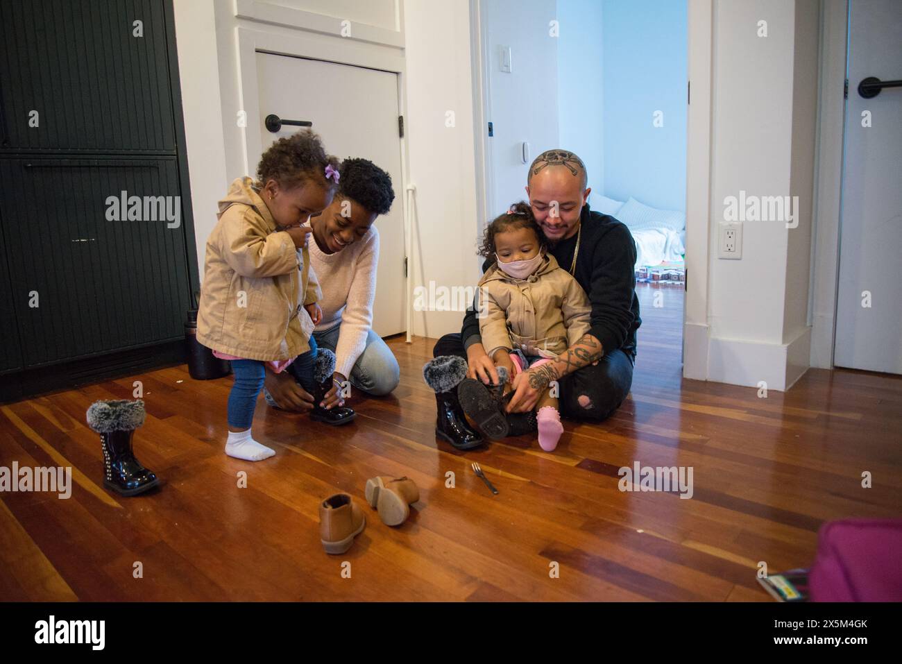 Genitori e figlie che si mettono le scarpe Foto Stock