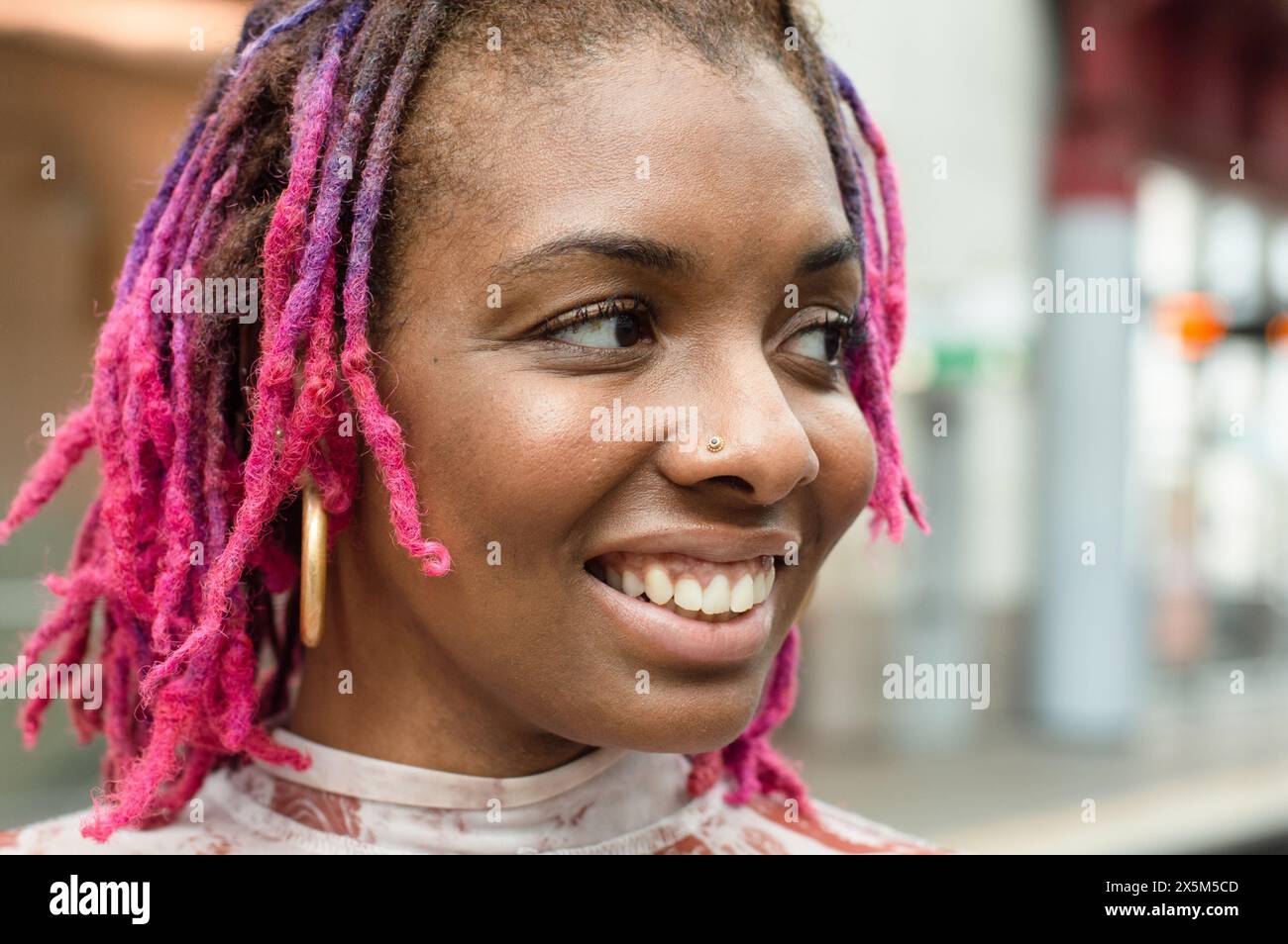 Primo piano di una donna sorridente con dreadlock colorati Foto Stock