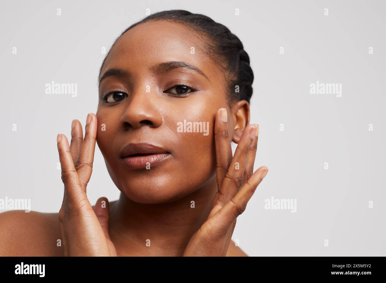 Ritratto in studio di una donna che tocca il viso Foto Stock