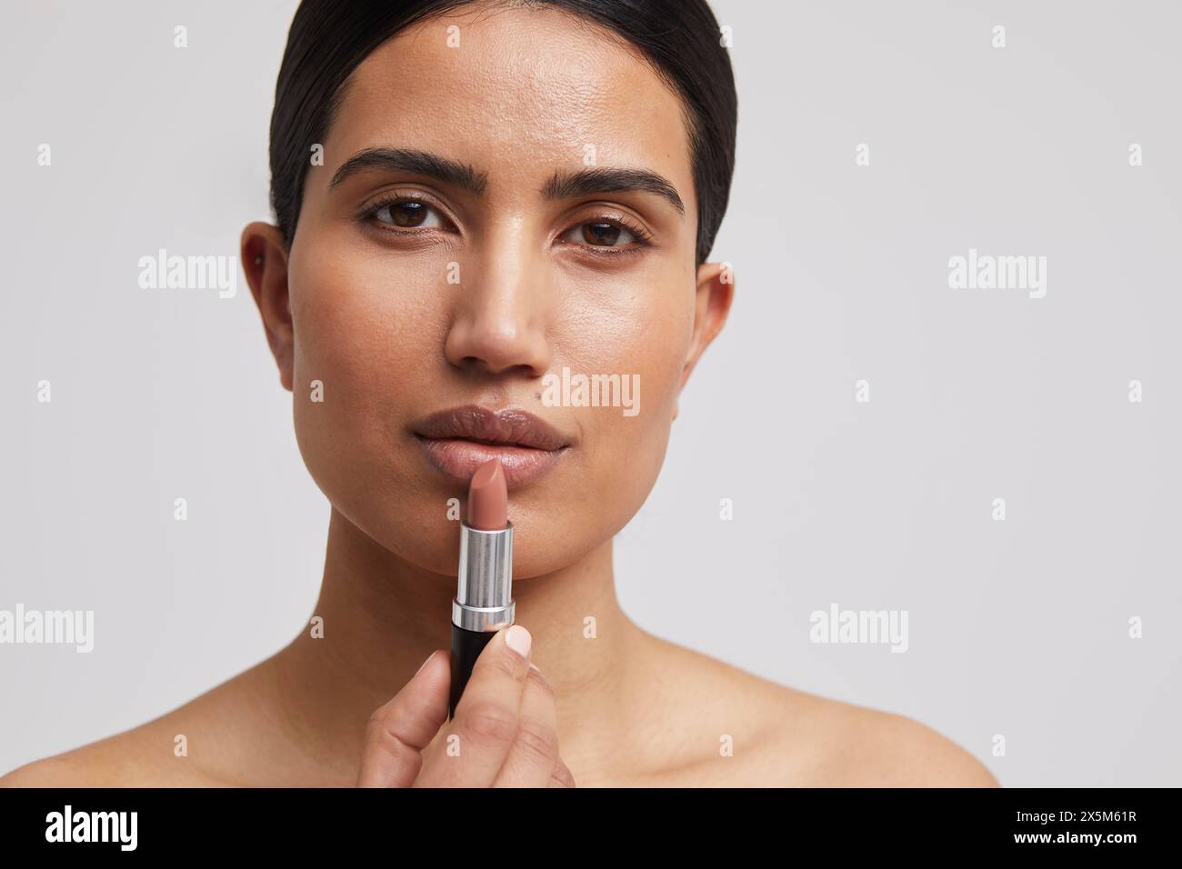 Ritratto in studio di una donna che applica il rossetto Foto Stock