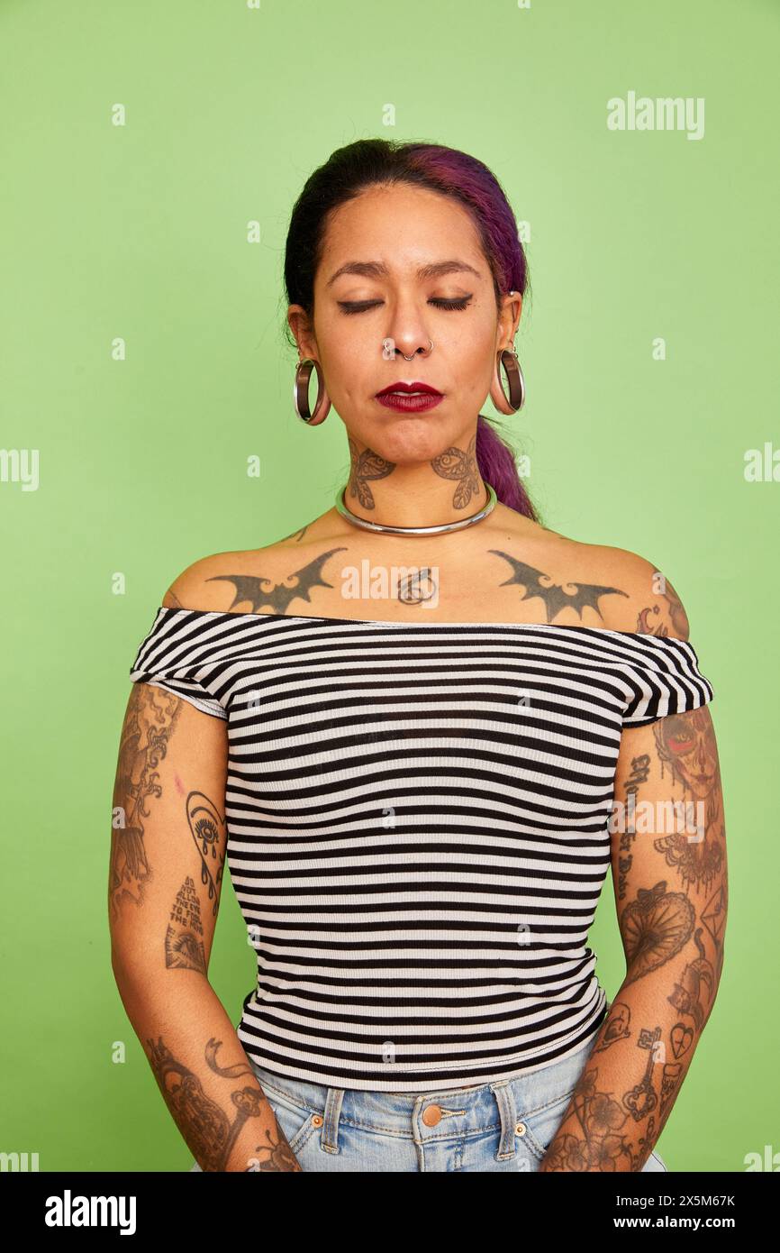Ritratto in studio di una donna trafitto con tatuaggi Foto Stock