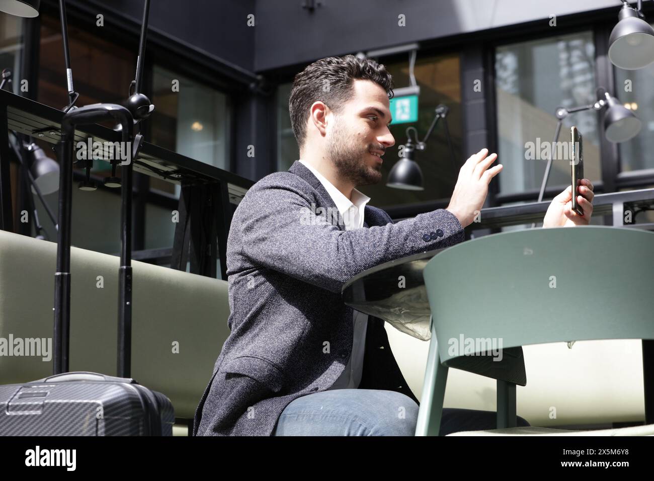 Un uomo d'affari sorridente che ha una videochiamata al telefono Foto Stock