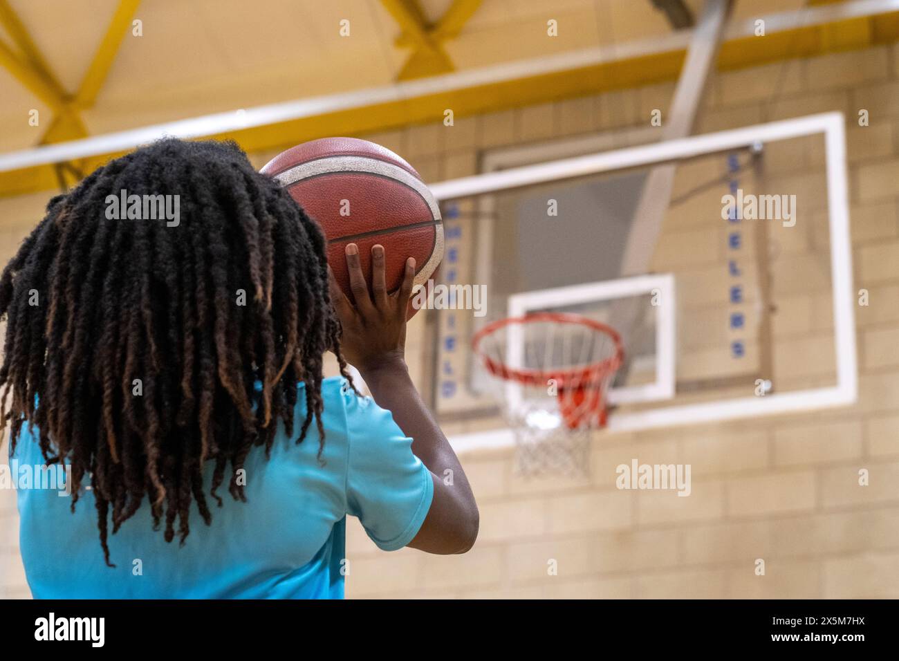 Ragazza adolescente che gioca a pallone sul campo da basket Foto Stock