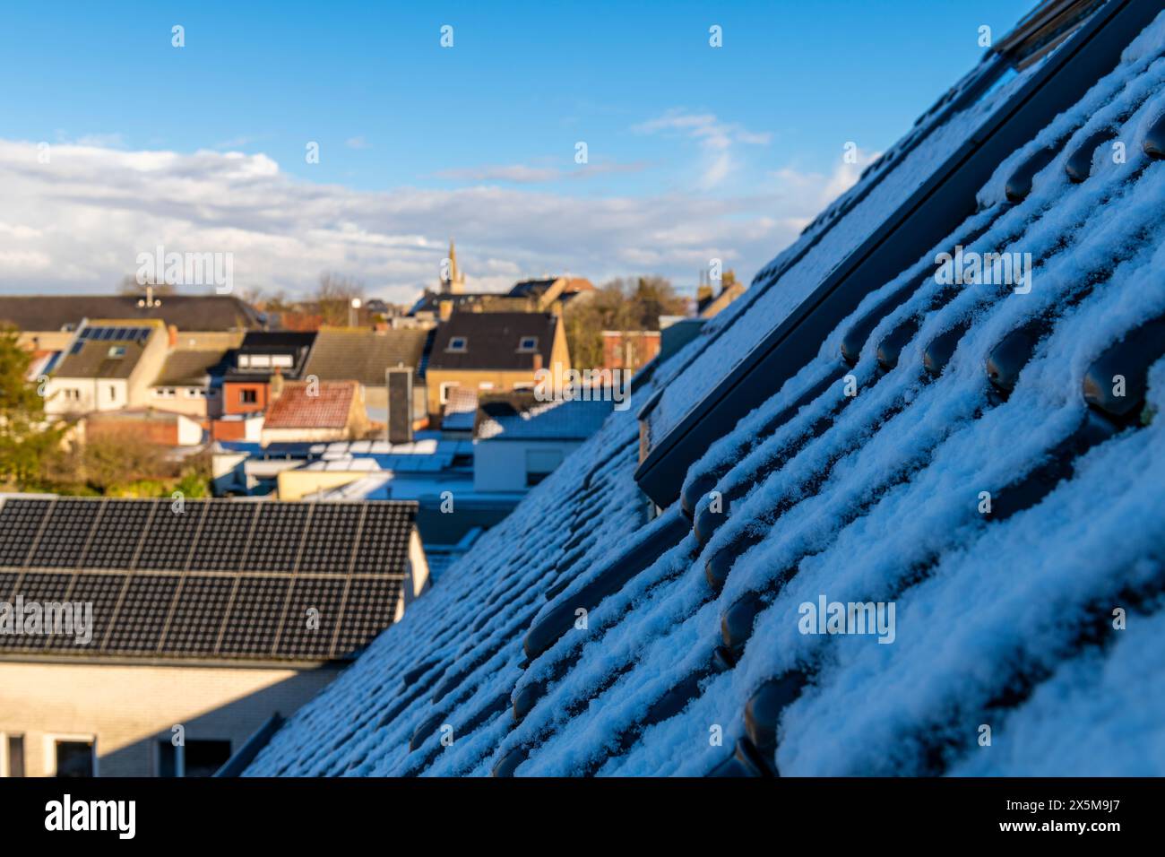 Neve su un tetto con lo skyline di Gistel in inverno, Fiandre occidentali, Belgio. Foto Stock