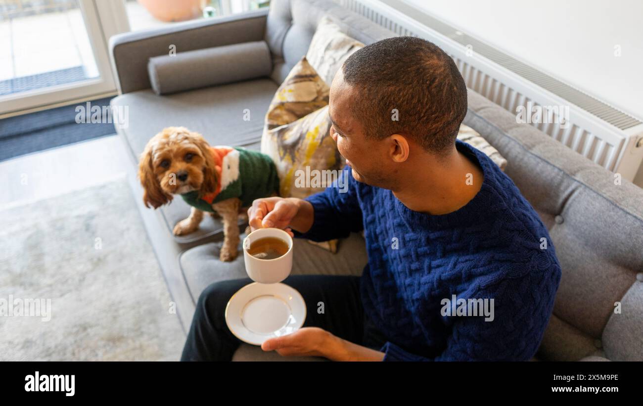 Uomo con cane seduto sul divano Foto Stock