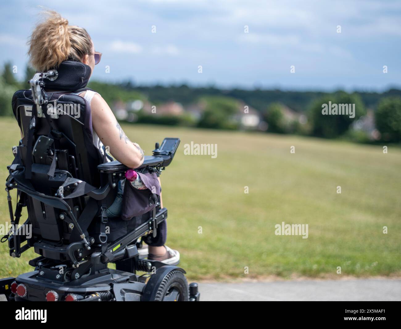 Donna in sedia a rotelle elettrica che va a piedi Foto Stock