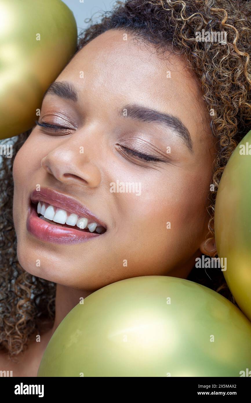 Primo piano di una donna sorridente con palloncini d'oro Foto Stock