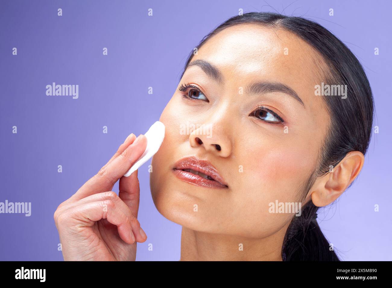 Ritratto in studio di una donna che pulisce il viso con un tampone di cotone Foto Stock