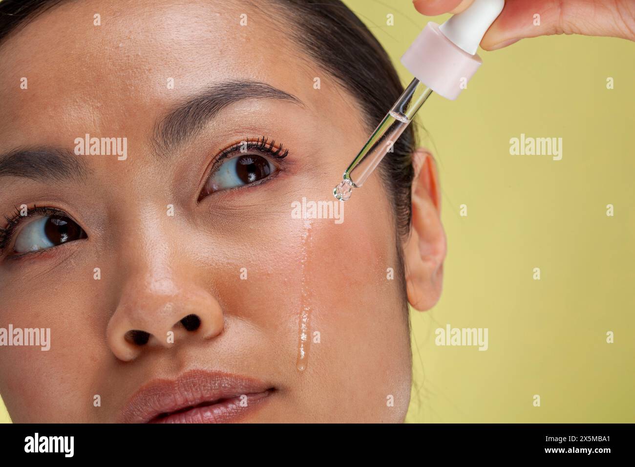 Primo piano di una donna che applica siero sul viso Foto Stock
