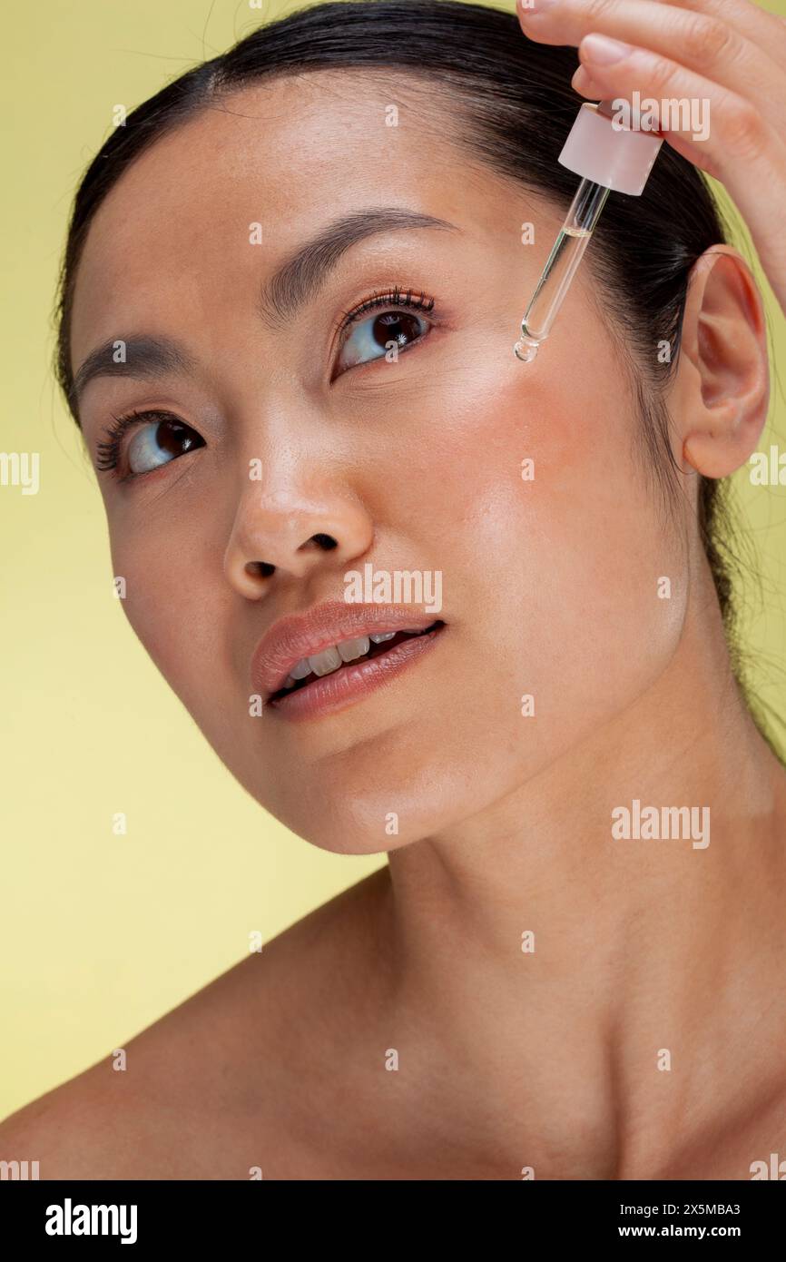 Primo piano di una donna che applica siero sul viso Foto Stock