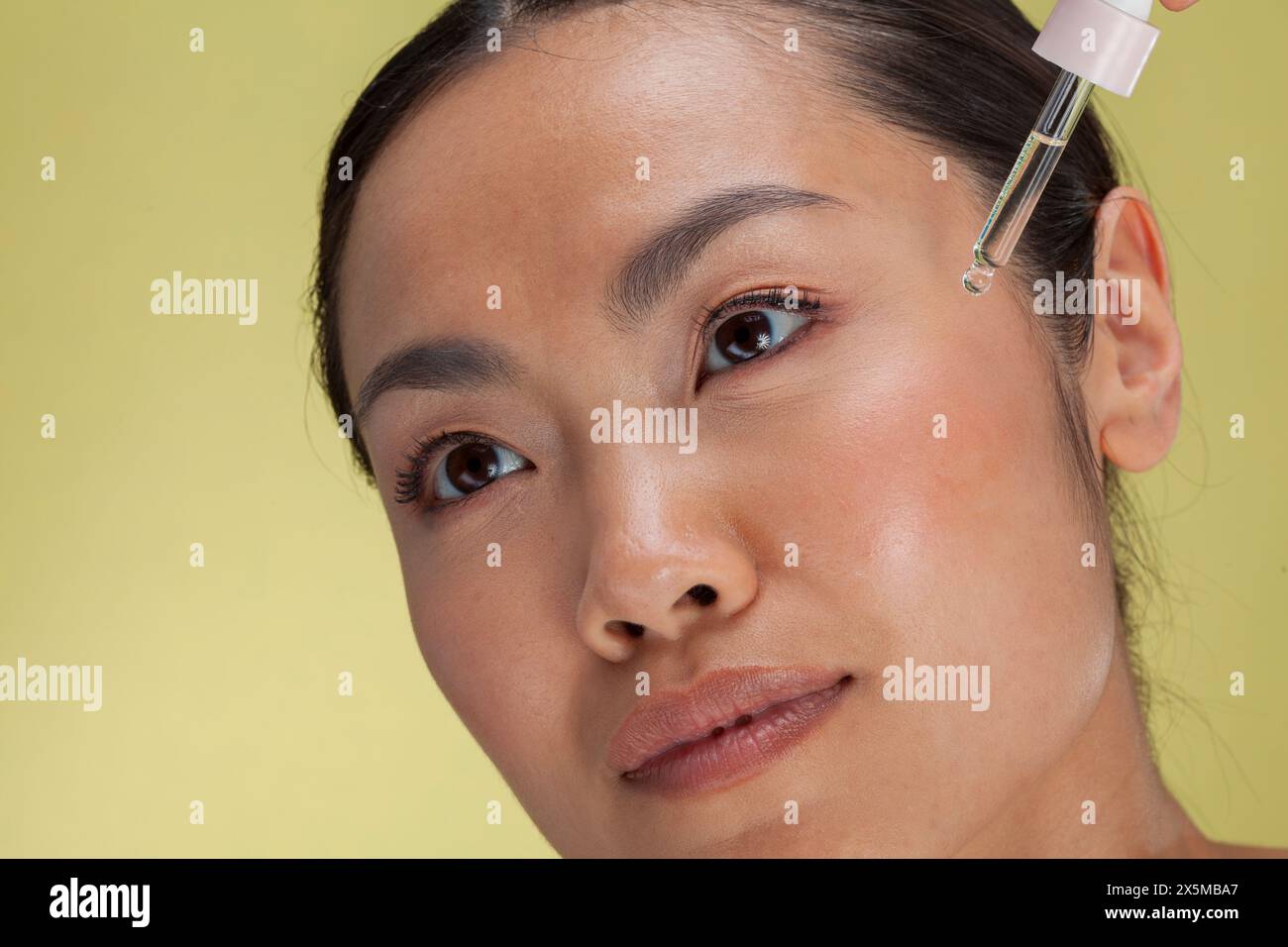 Primo piano di una donna che applica siero sul viso Foto Stock