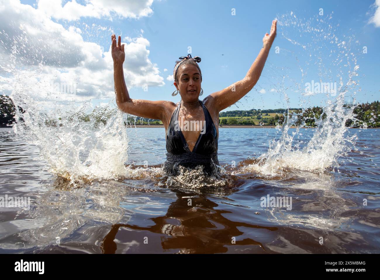 Donna che spruzza acqua nel lago, Yorkshire, Regno Unito Foto Stock