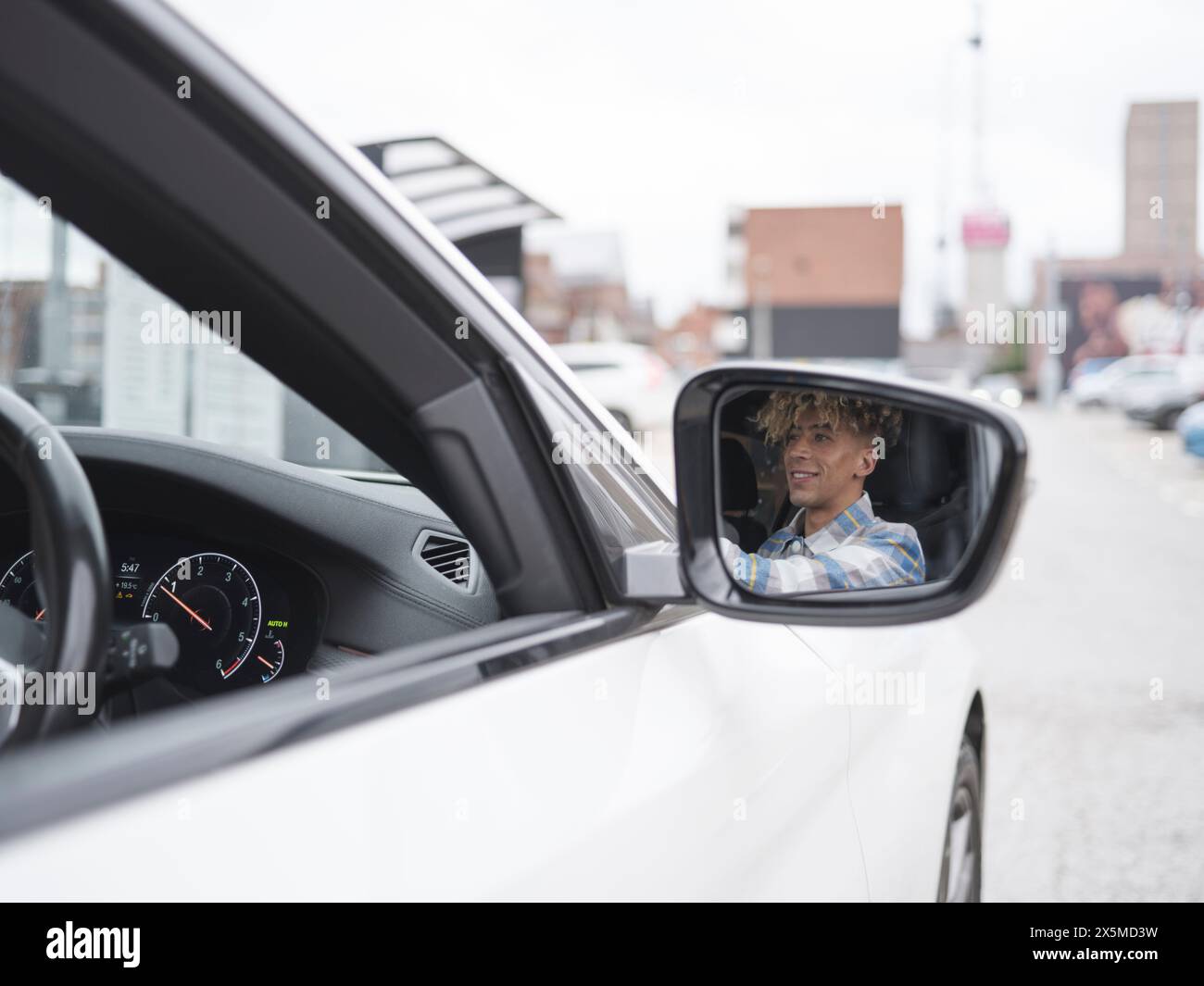 Riflesso di un uomo sorridente nello specchio laterale Foto Stock