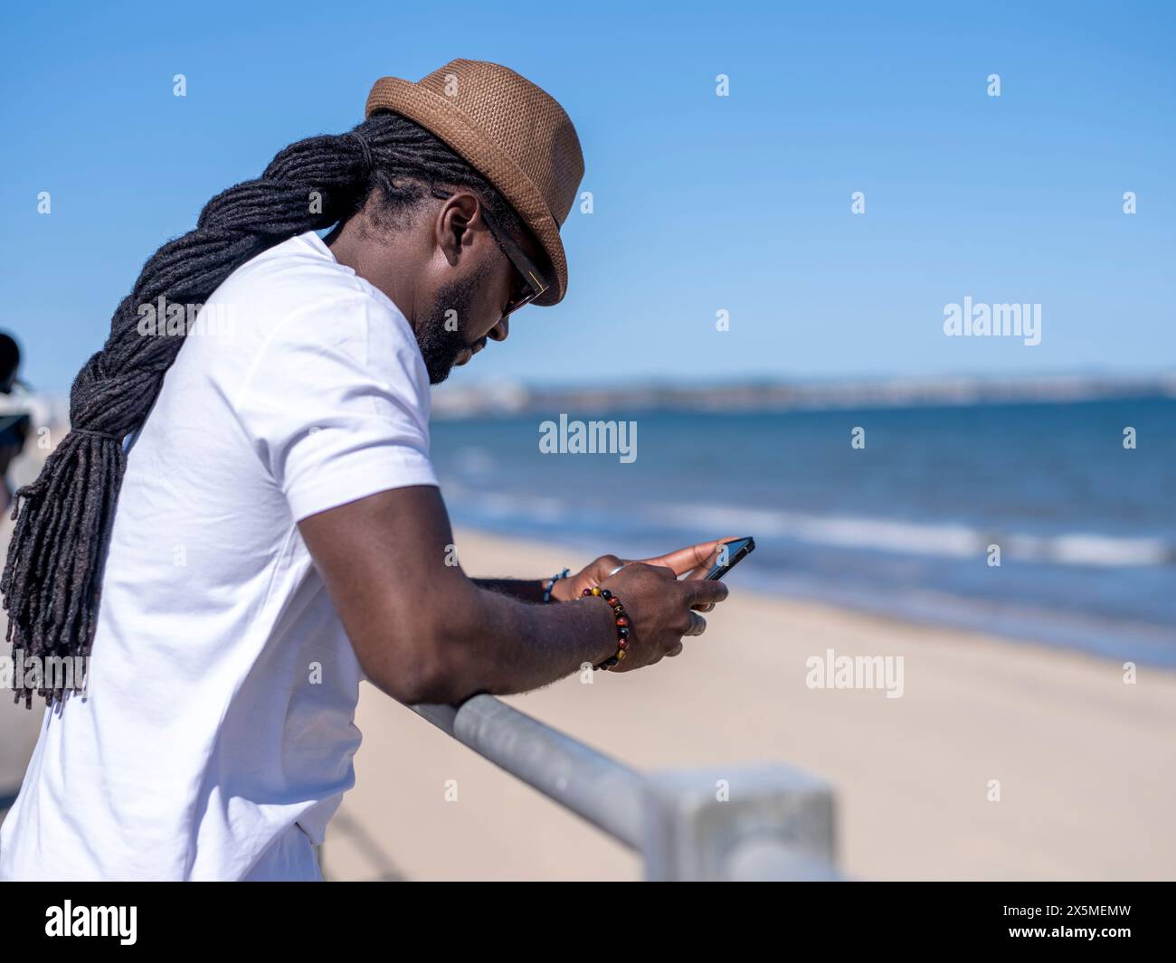 Uomo che usa il telefono sulla spiaggia Foto Stock