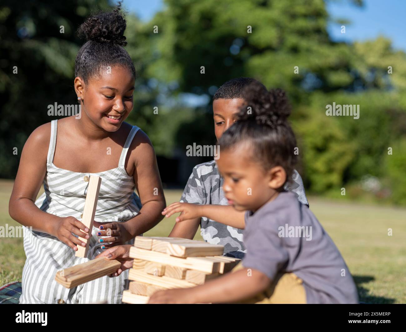 Fratelli (2-3, 8-9, 10-11) che giocano a un gioco di rimozione dei blocchi Foto Stock