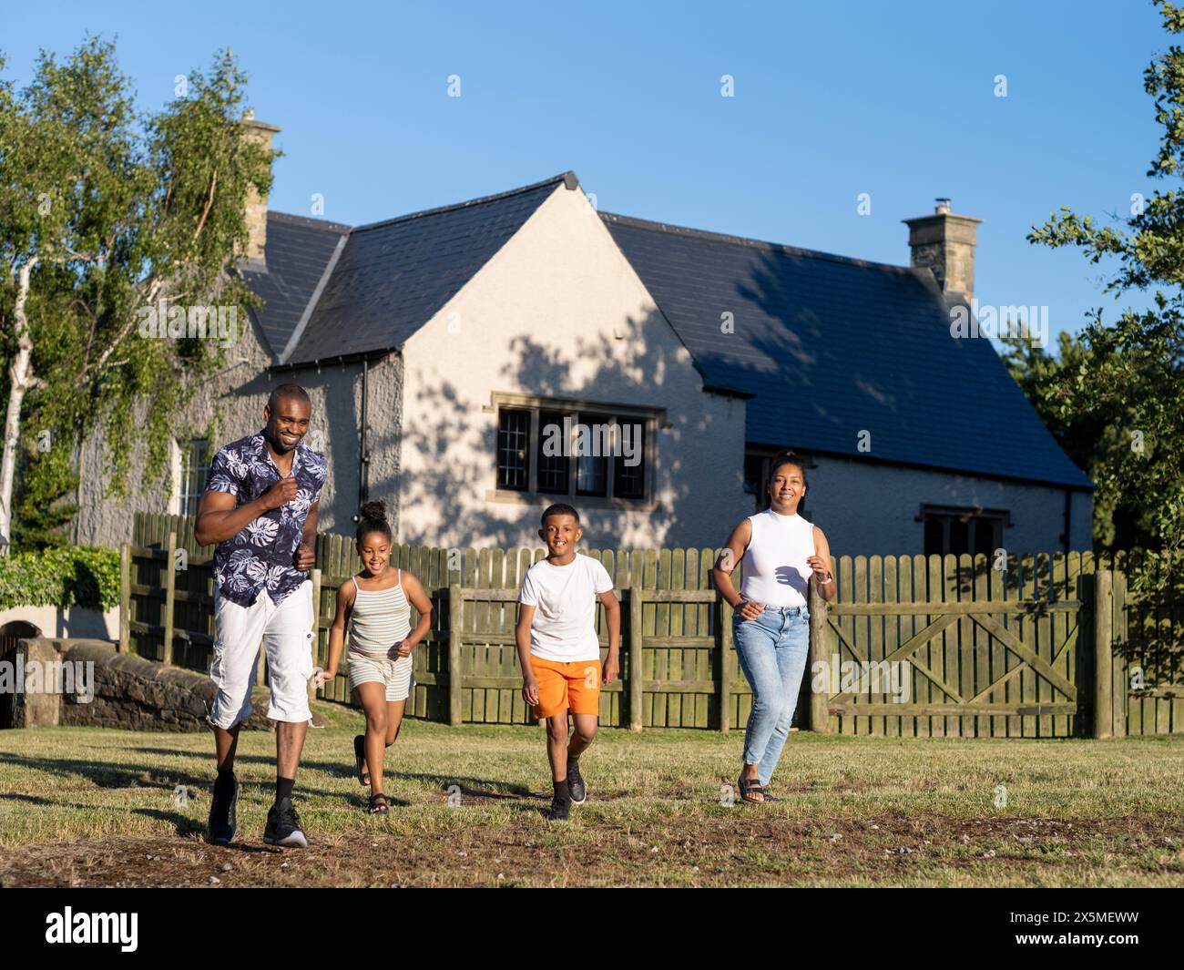 Famiglia con bambini (8-9, 10-11) che corrono in campagna Foto Stock