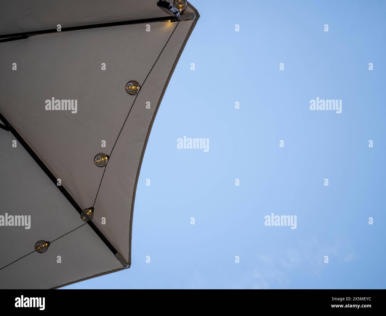 Tendina parasole con luci a corda contro il cielo blu Foto Stock