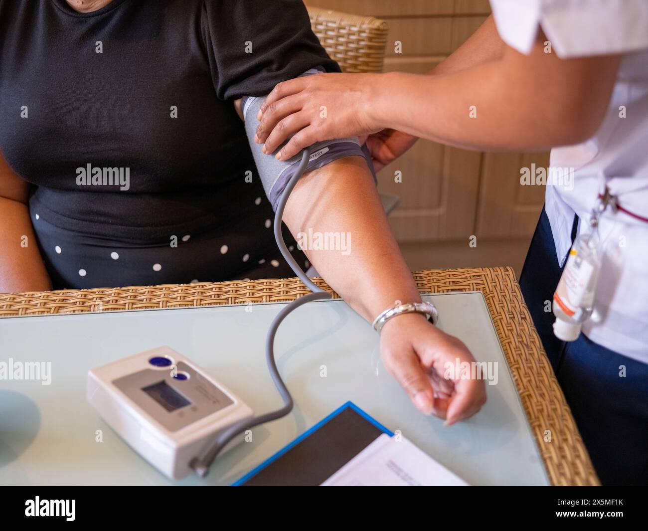 Infermiera che misura la pressione sanguigna di una donna matura Foto Stock