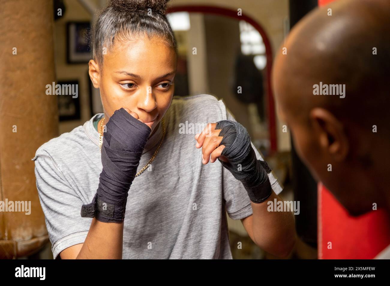 Giovane donna e allenatore che si preparano per la partita di boxe Foto Stock