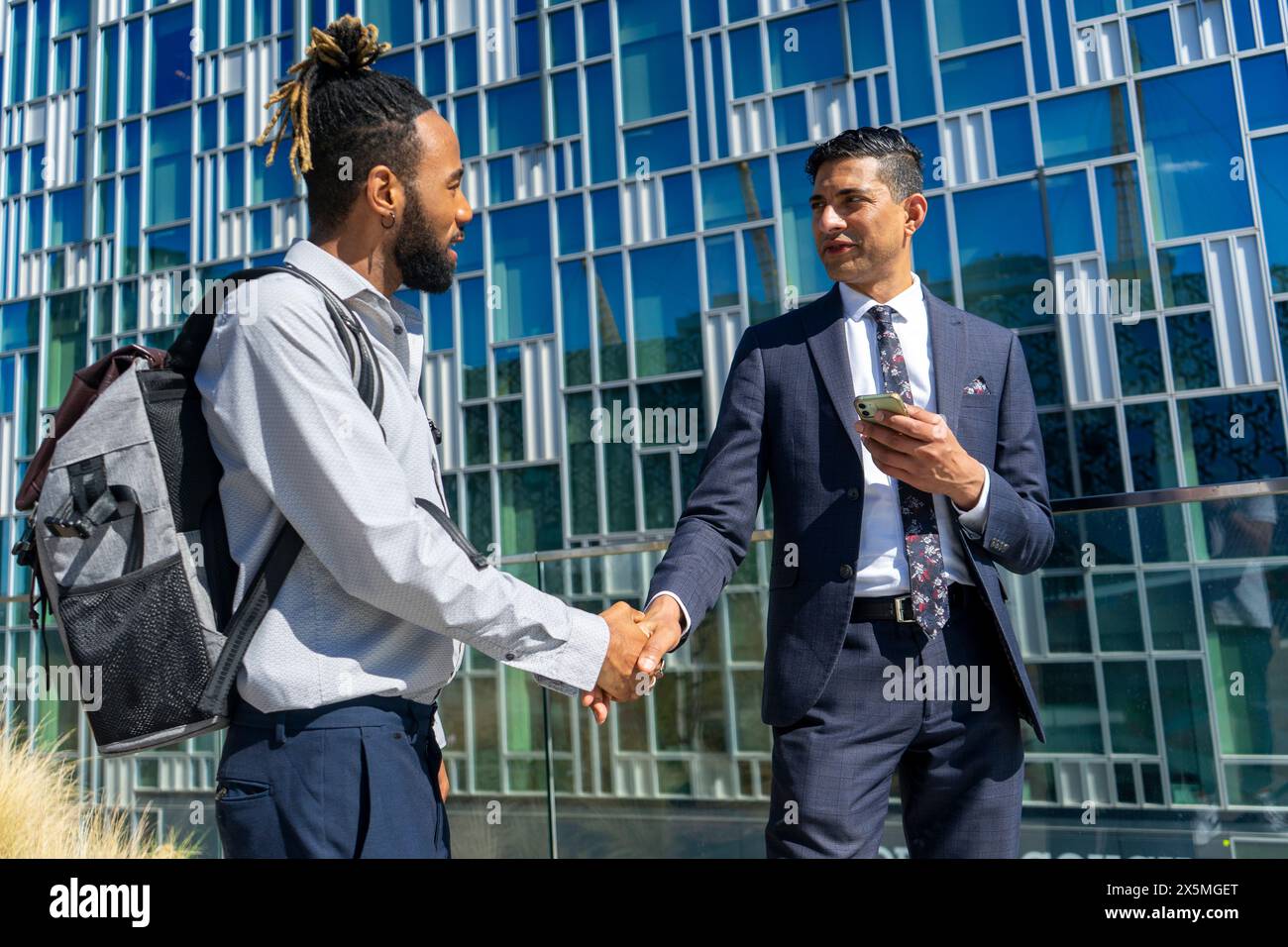 Due uomini d'affari che stringono la mano nel quartiere degli affari Foto Stock
