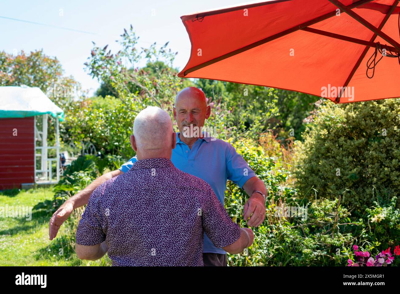 Coppia di uomini anziani che abbracciano in giardino Foto Stock