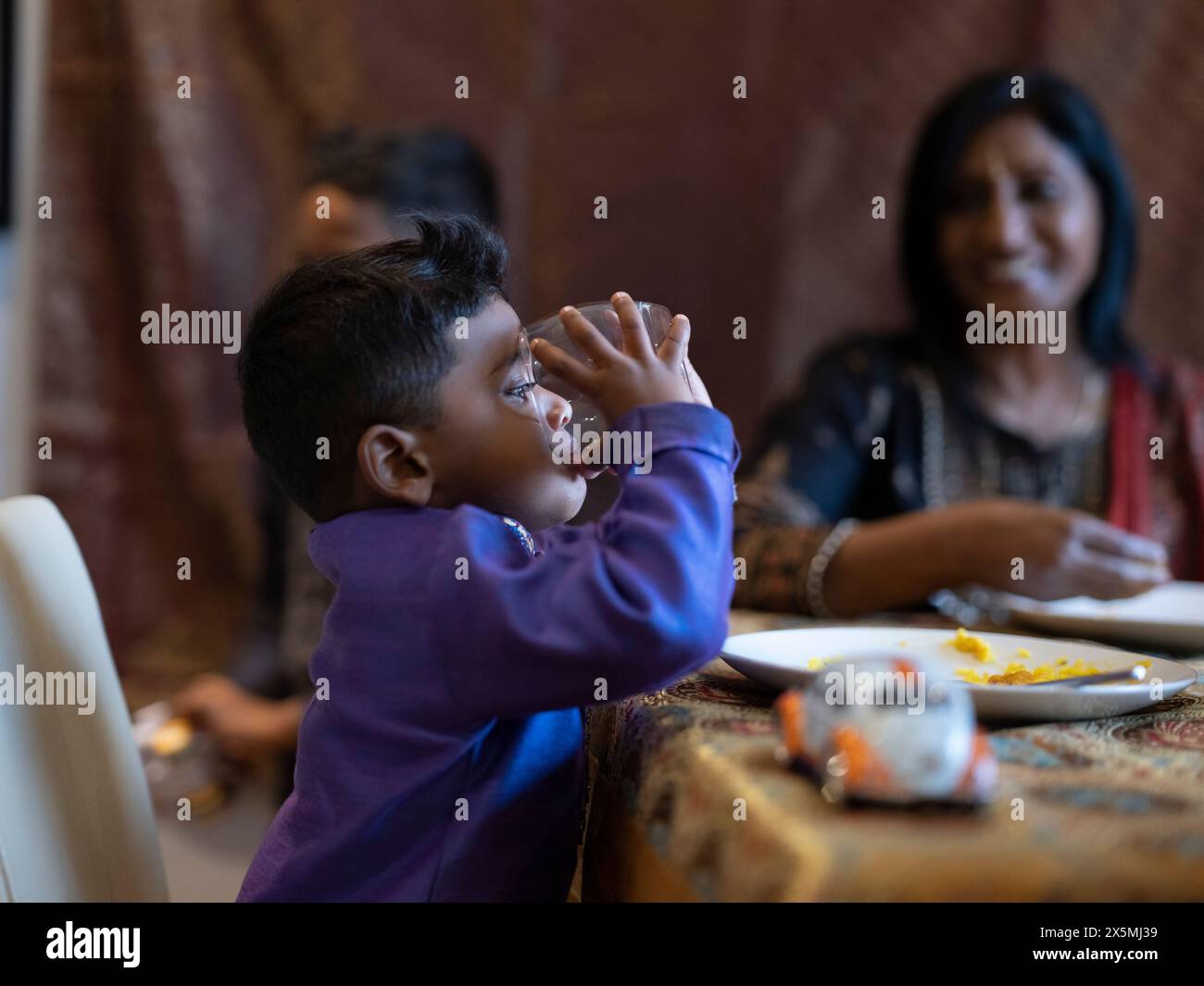 Ragazzo che beve dal bicchiere alla cena Diwali Foto Stock