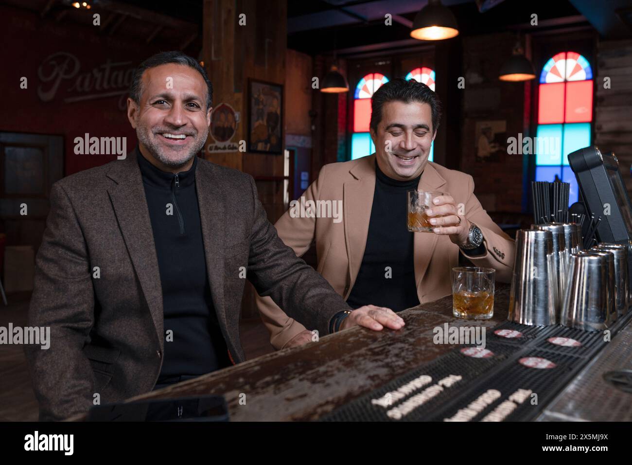 Uomini maturi sorridenti seduti al bar Foto Stock