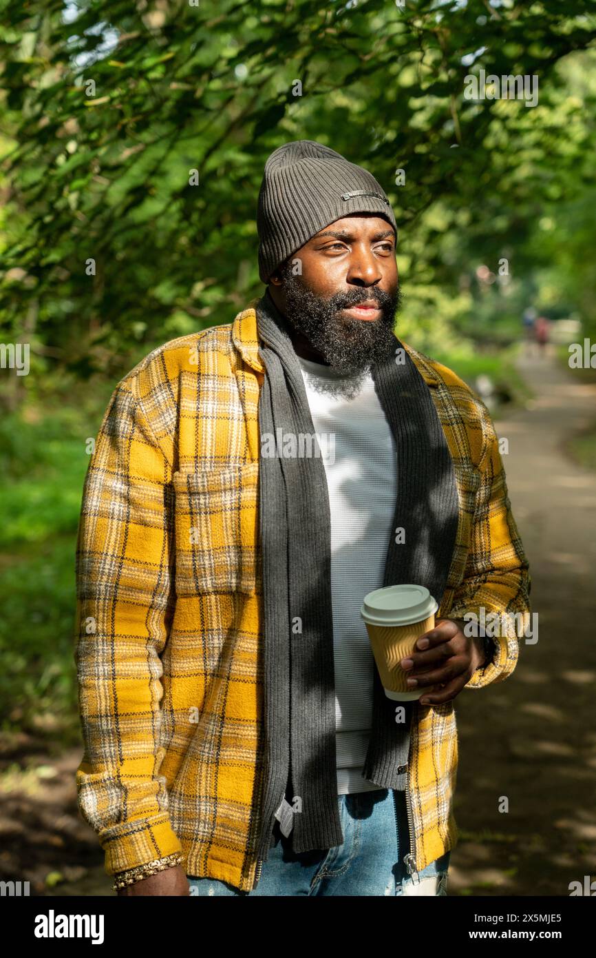 Uomo con tazza usa e getta nel parco in autunno Foto Stock