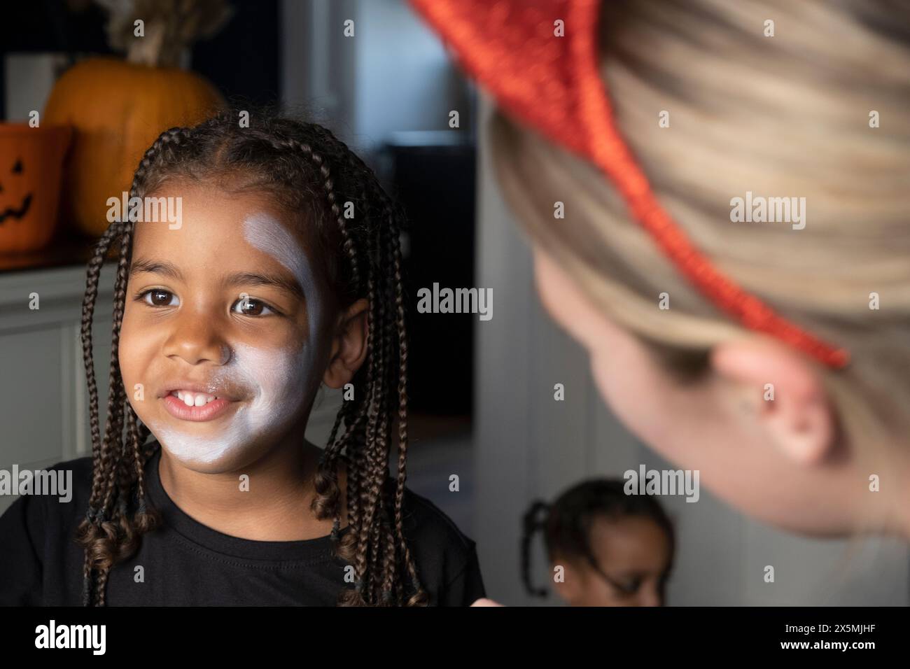 Primo piano di donne e figli che affrontano con vernice bianca sul viso per Halloween Foto Stock